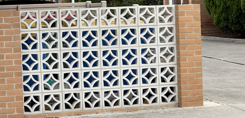 Fence made from cutout Besser blocks. The fence is 5 blocks high and 8 blocks across. Each block has a quarter semi-circular pattern.